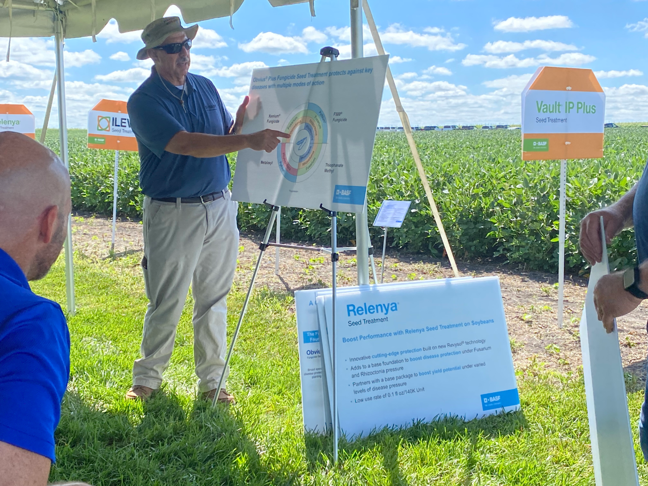 Man standing in front of a field pointing at a chart